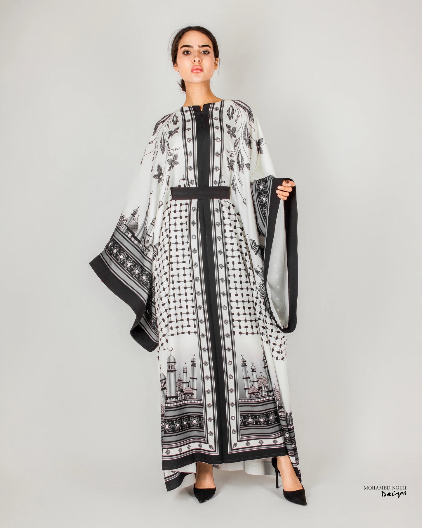 Elegant black and white gown with intricate Palestinian shawl-inspired patterns, featuring mosque motifs and geometric designs. Visit www.mnourdesign.com for more.