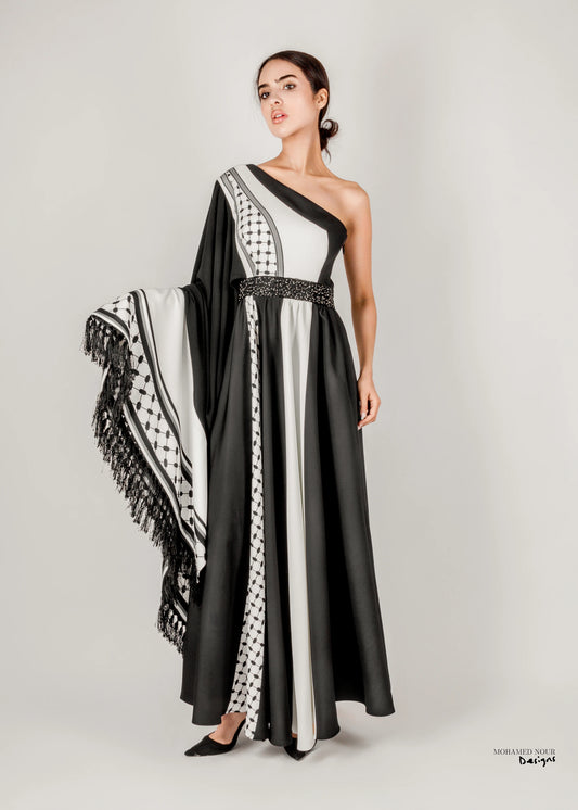 Elegant black and white gown with Palestinian shawl-inspired patterns, featuring geometric designs and fringe details. Visit www.mnourdesign.com for more