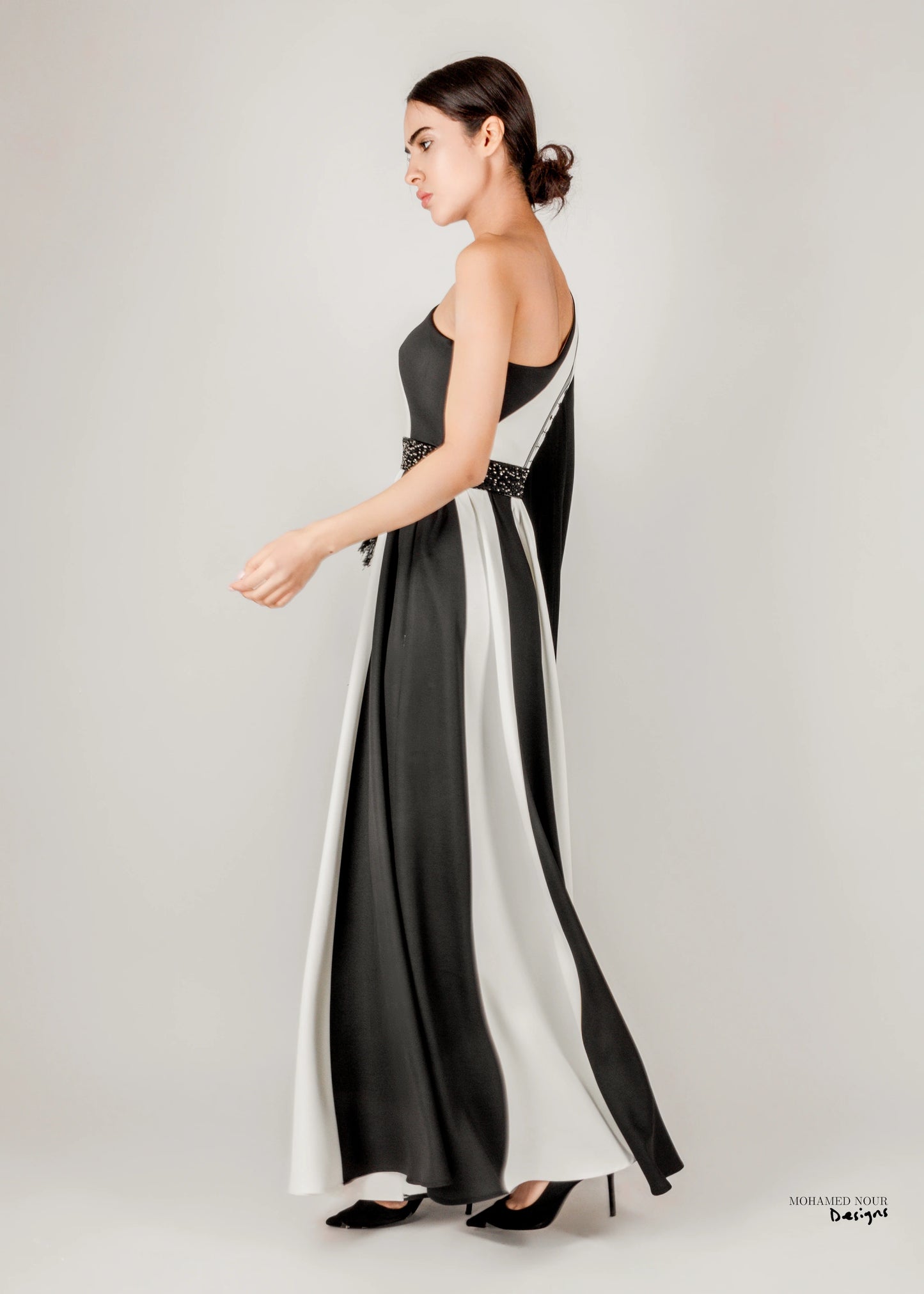 Elegant black and white gown with Palestinian shawl-inspired patterns, featuring geometric designs and fringe details. Visit www.mnourdesign.com for more