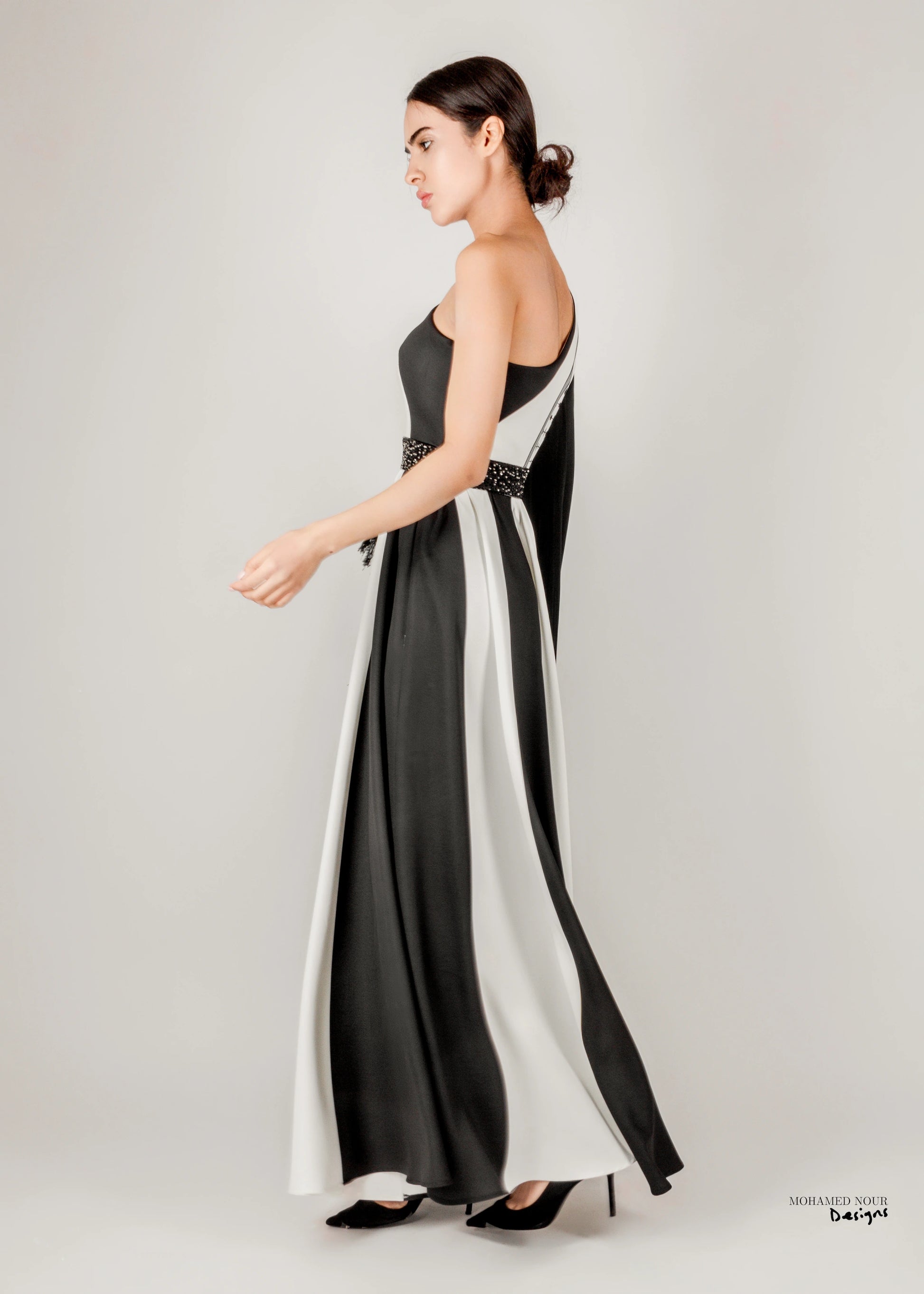 Elegant black and white gown with Palestinian shawl-inspired patterns, featuring geometric designs and fringe details. Visit www.mnourdesign.com for more