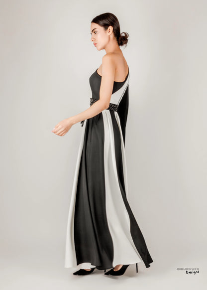 Elegant black and white gown with Palestinian shawl-inspired patterns, featuring geometric designs and fringe details. Visit www.mnourdesign.com for more