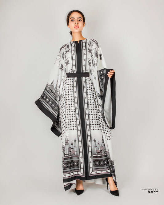 Elegant black and white gown with intricate Palestinian shawl-inspired patterns, featuring mosque motifs and geometric designs. Visit www.mnourdesign.com for more.