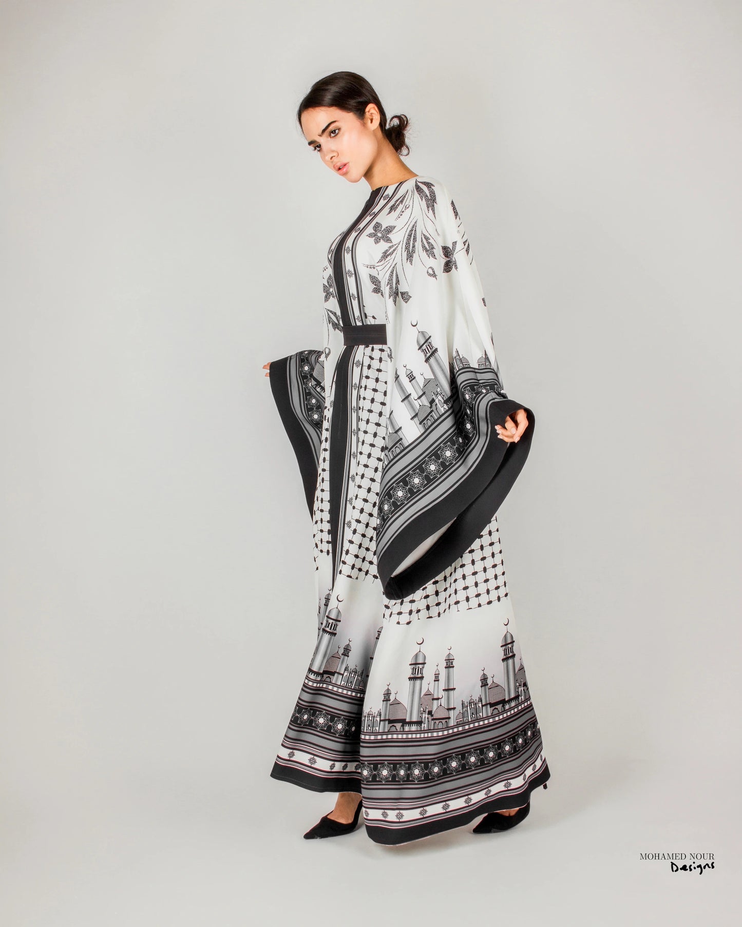 Elegant black and white gown with intricate Palestinian shawl-inspired patterns, featuring mosque motifs and geometric designs. Visit www.mnourdesign.com for more.
