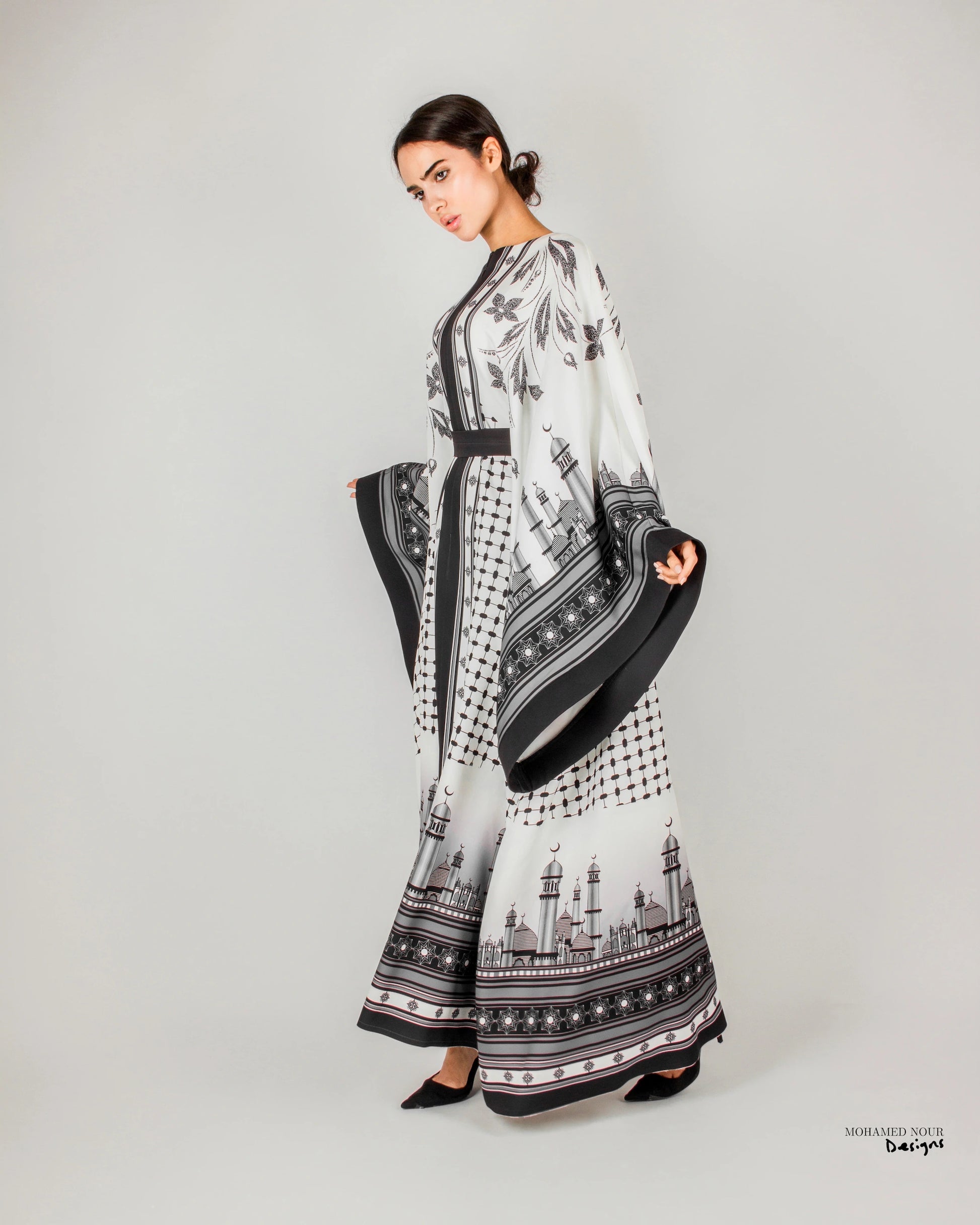 Elegant black and white gown with intricate Palestinian shawl-inspired patterns, featuring mosque motifs and geometric designs. Visit www.mnourdesign.com for more.