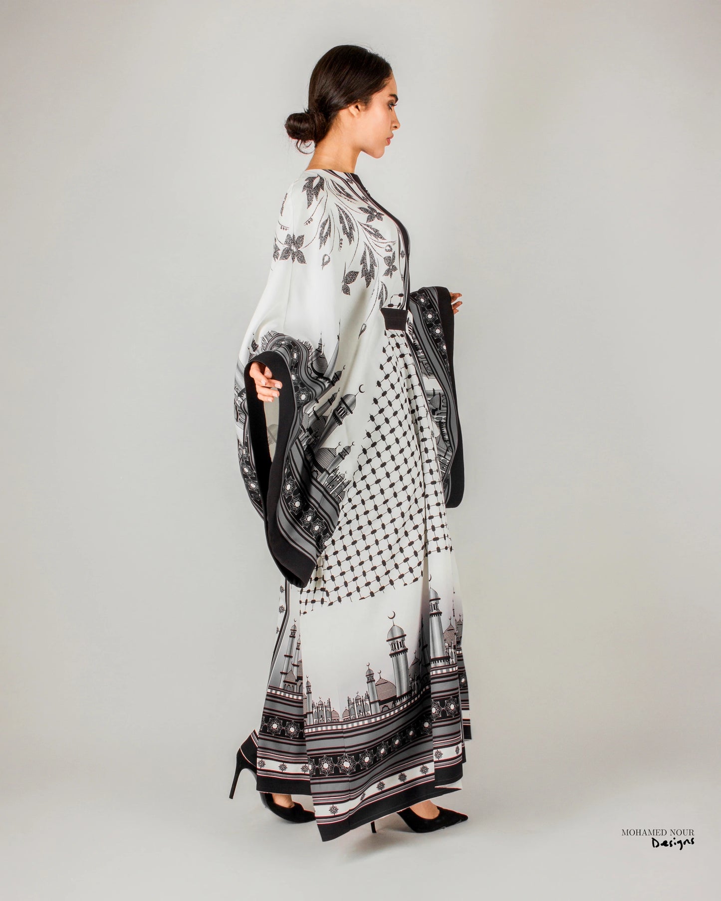 Elegant black and white gown with intricate Palestinian shawl-inspired patterns, featuring mosque motifs and geometric designs. Visit www.mnourdesign.com for more.