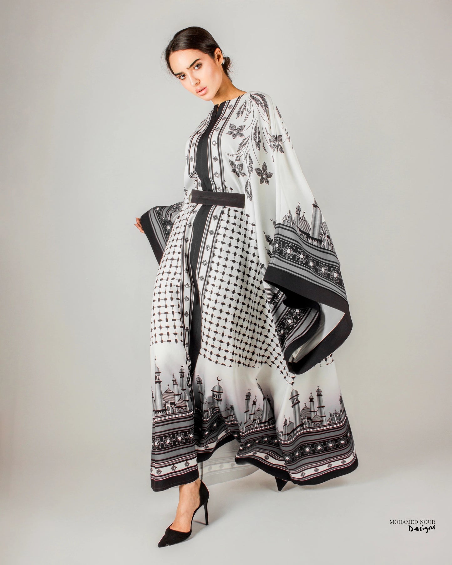 Elegant black and white gown with intricate Palestinian shawl-inspired patterns, featuring mosque motifs and geometric designs. Visit www.mnourdesign.com for more.
