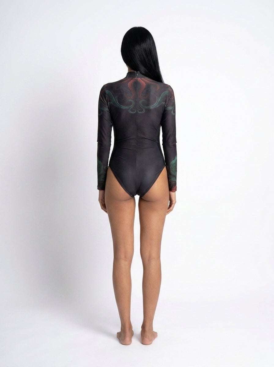 A model viewed from the back wearing a black long-sleeve bodysuit with a subtle green and red graphic pattern on the upper back and shoulders, set against a plain white studio background.