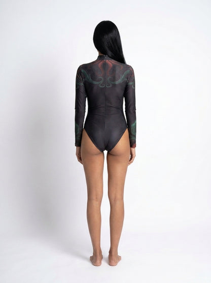 A model viewed from the back wearing a black long-sleeve bodysuit with a subtle green and red graphic pattern on the upper back and shoulders, set against a plain white studio background.