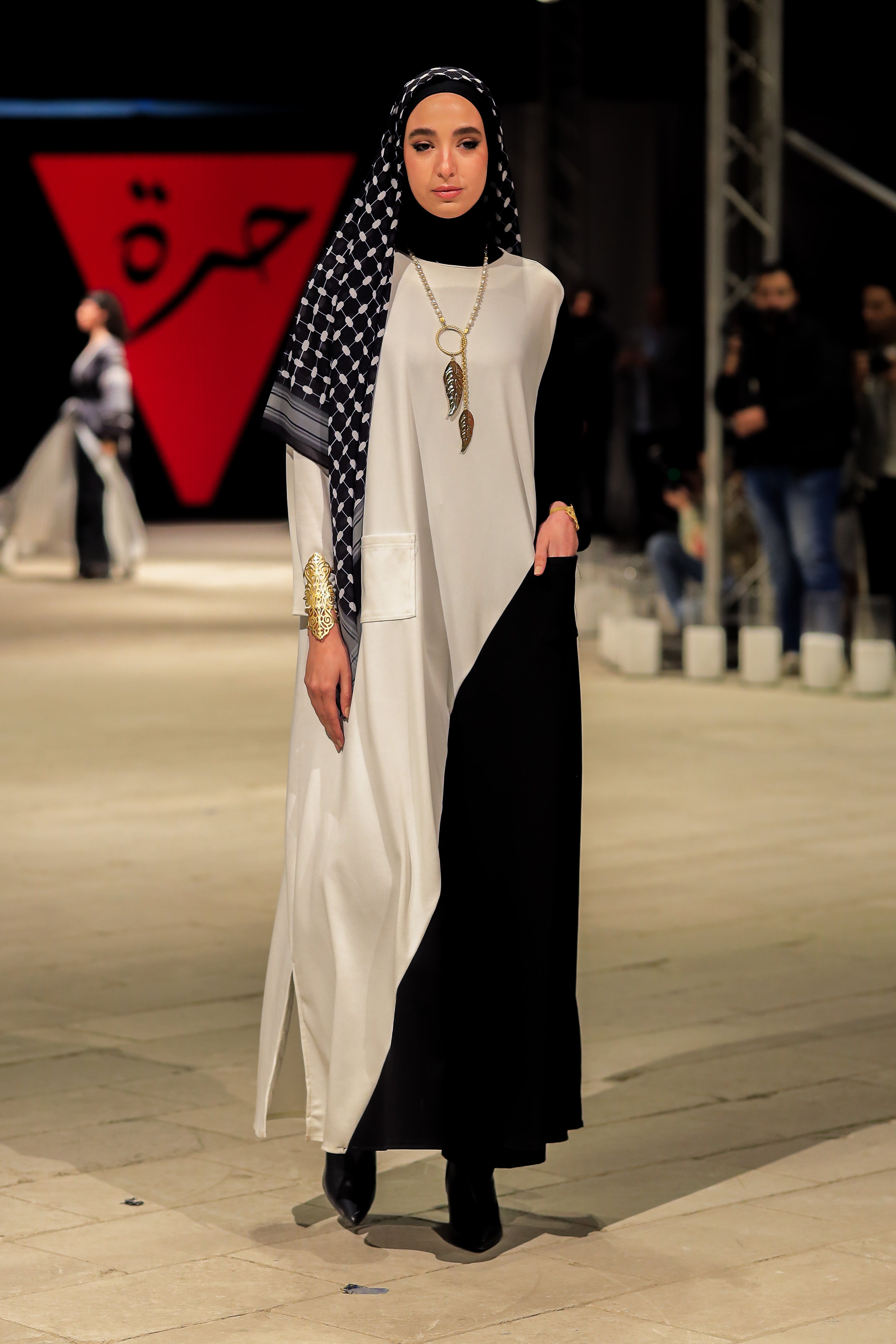 A stunning model gracefully poses in an elegant dress from the Horra Collection by designer Mohamed Nour, showcasing intricate details and luxurious craftsmanship