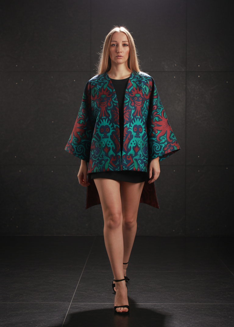 Model wearing a teal and red patterned jacket on a black background