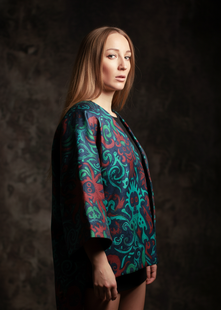 Woman wearing a colorful patterned jacket against a dark background