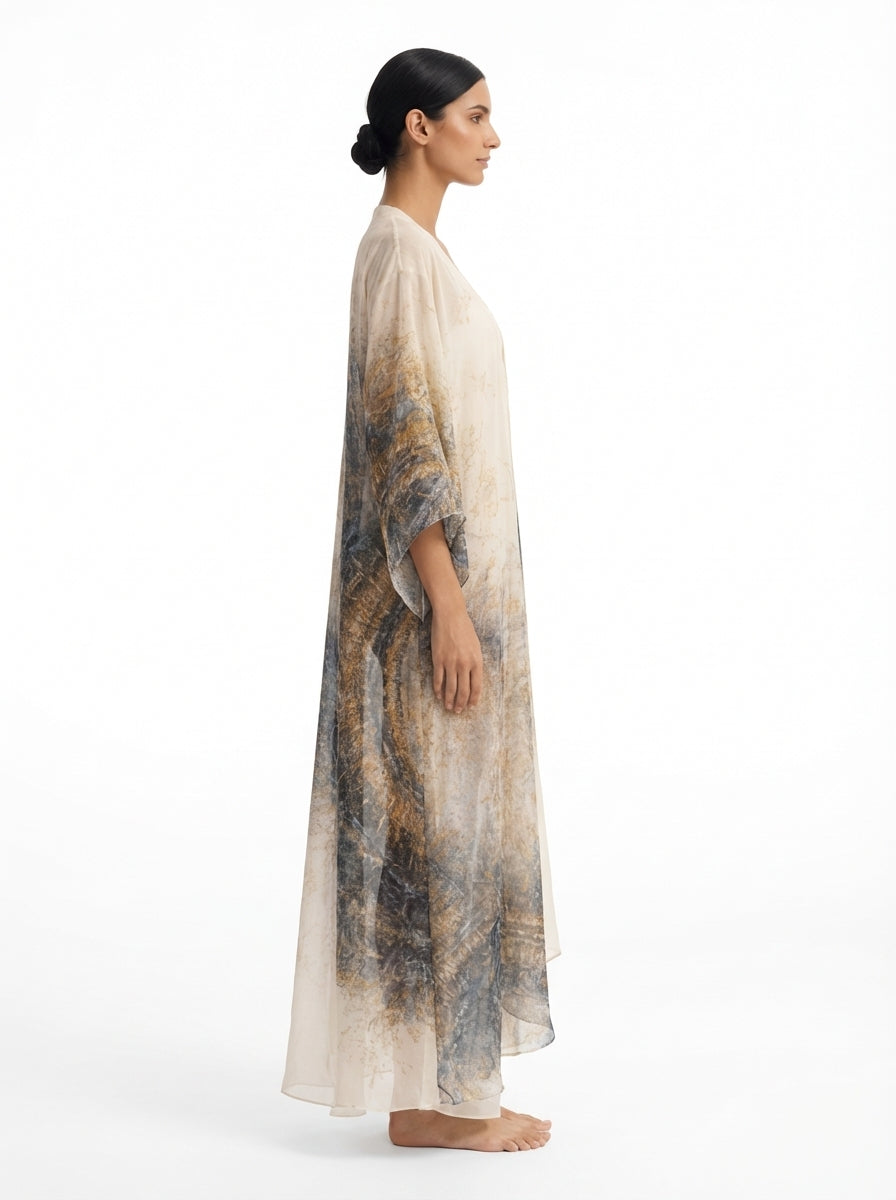 Woman wearing a long, light-colored dress with a patterned design on a white background