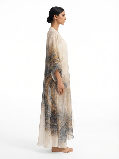 Woman wearing a long, light-colored dress with a patterned design on a white background