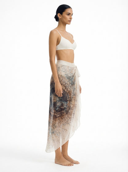 Woman wearing a white bikini and a long, patterned skirt on a white background