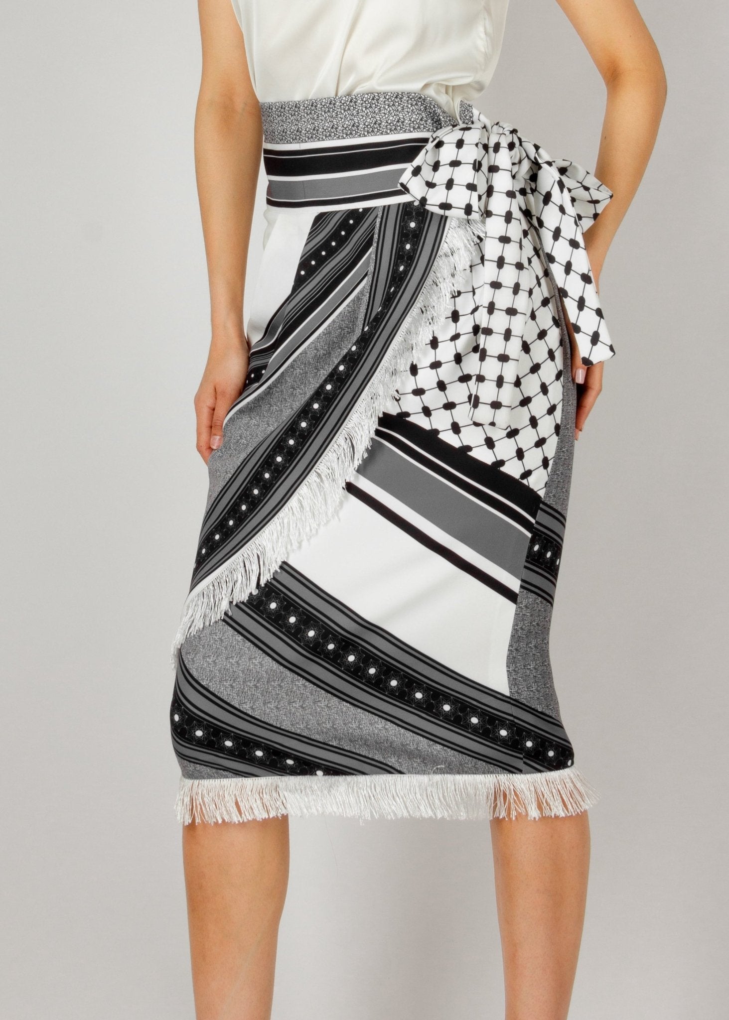 Chic wrap-style midi skirt from the HORRA collection by MNour Design, featuring a striking black-and-white traditional pattern with fringe detailing and a statement side tie. Paired with a sleek satin top and classic heels for an effortlessly elegant look. Explore more at www.mnourdesign.com