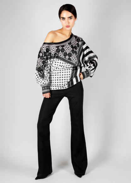 Bold off-shoulder blouse from the HORRA collection by MNour Design, featuring a striking keffiyeh-inspired pattern with intricate geometric details. Paired with sleek black trousers for a modern, sophisticated look. Explore more at www.mnourdesign.com