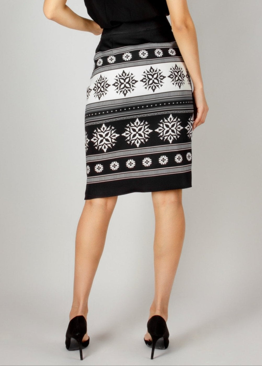 Chic black and white pencil skirt from the HORRA collection by MNour Design, featuring traditional keffiyeh-inspired embroidery. Paired with a sleek black V-neck top and classic black heels for an elegant yet modern look. Discover more at www.mnourdesign.com.