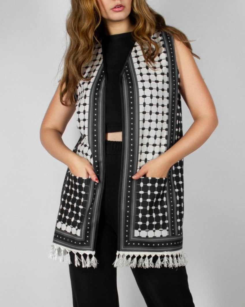 Modern black and white vest from the HORRA collection by MNour Design, featuring intricate geometric and traditional patterns with delicate fringe detailing. Styled over a sleek black ensemble for a contemporary yet culturally inspired look. Discover more at www.mnourdesign.com