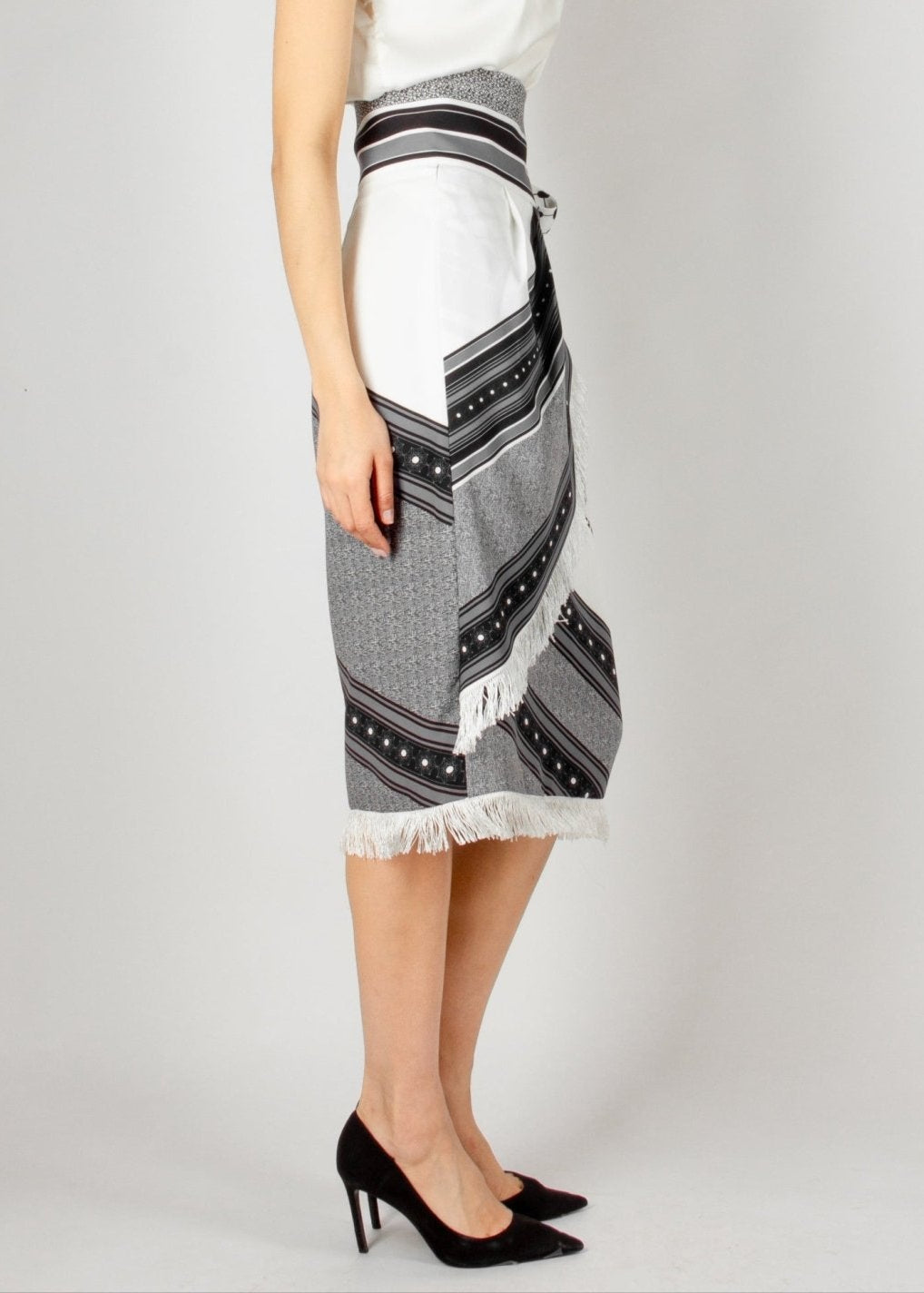 Chic wrap-style midi skirt from the HORRA collection by MNour Design, featuring a striking black-and-white traditional pattern with fringe detailing and a statement side tie. Paired with a sleek satin top and classic heels for an effortlessly elegant look. Explore more at www.mnourdesign.com