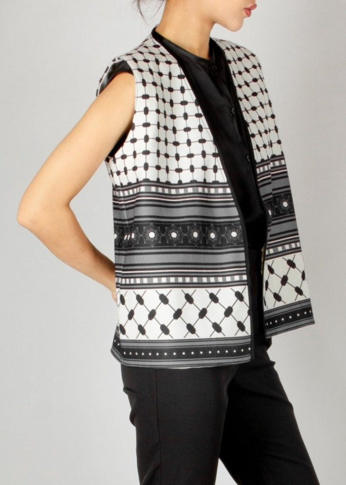 Modern sleeveless vest from the HORRA collection by MNour Design, featuring a striking black-and-white keffiyeh-inspired pattern. Styled with a sleek black satin blouse and tailored trousers for a bold and sophisticated look. Discover more at www.mnourdesign.com