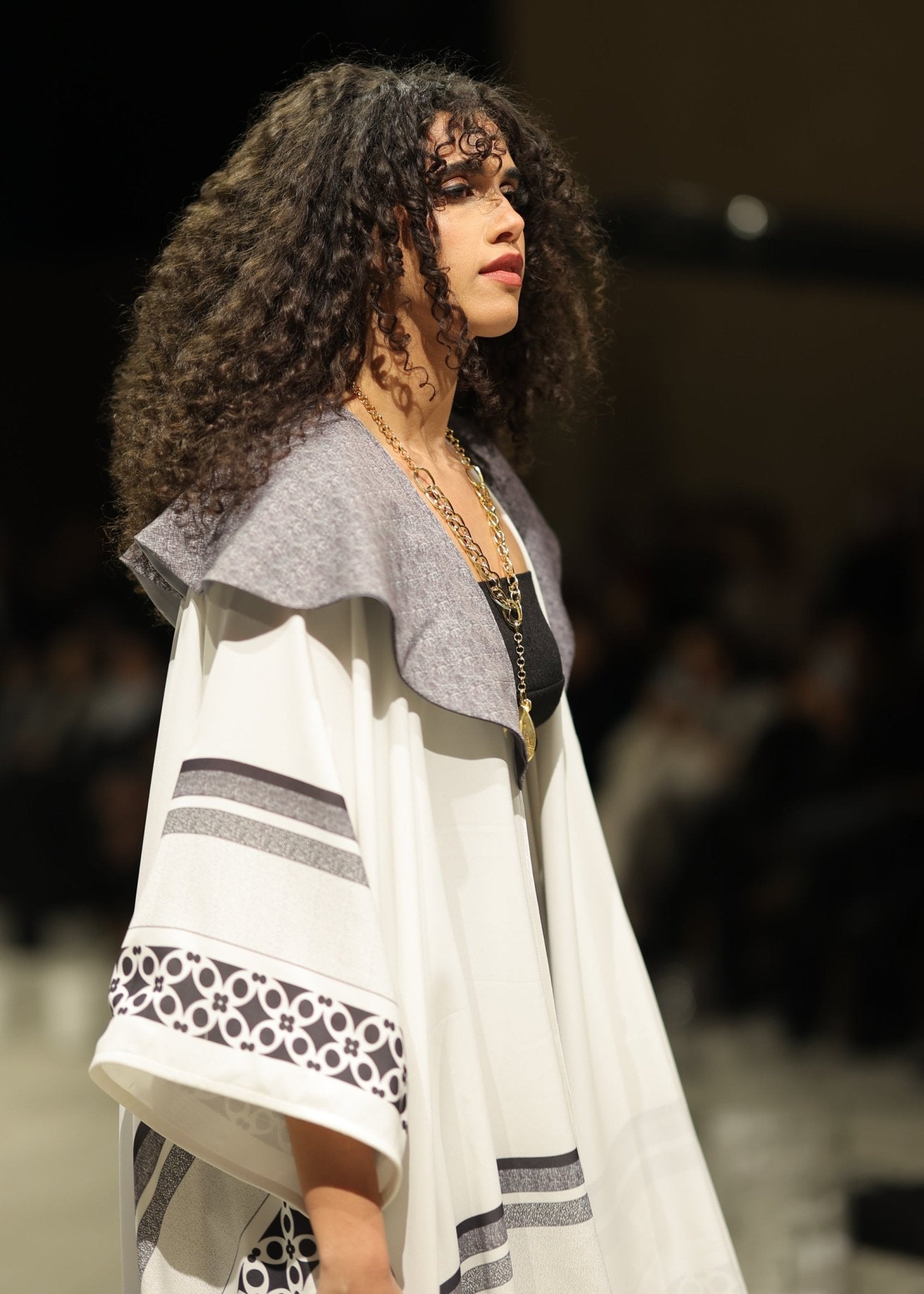 A striking black and white gradient kimono from the HORRA collection by MNour Design, showcased on the runway. Featuring traditional Palestinian keffiyeh-inspired patterns with a modern ombre effect, this elegant piece flows effortlessly, blending heritage with contemporary fashion. Explore the collection at www.mnourdesign.com