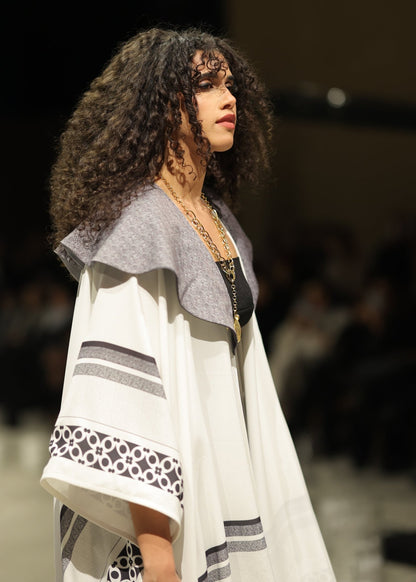 A striking black and white gradient kimono from the HORRA collection by MNour Design, showcased on the runway. Featuring traditional Palestinian keffiyeh-inspired patterns with a modern ombre effect, this elegant piece flows effortlessly, blending heritage with contemporary fashion. Explore the collection at www.mnourdesign.com