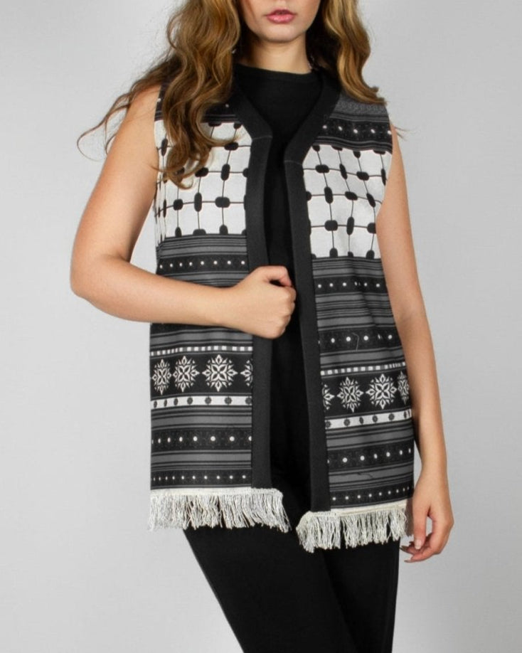 Modern black and white vest from the HORRA collection by MNour Design, featuring intricate geometric and traditional patterns with delicate fringe detailing. Styled over a sleek black ensemble for a contemporary yet culturally inspired look. Discover more at www.mnourdesign.com