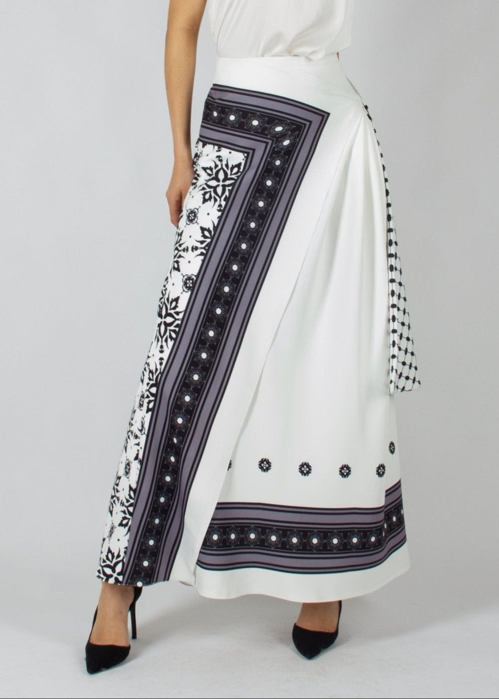 Elegant white maxi skirt from the HORRA collection by MNour Design, featuring intricate traditional-inspired patterns and a draped keffiyeh detail for a bold cultural statement. Paired with a sleek satin top and classic heels for a refined, sophisticated look. Discover more at www.mnourdesign.com