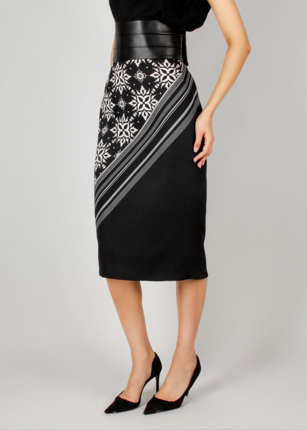 Elegant black midi skirt from the HORRA collection by MNour Design, featuring a bold asymmetrical keffiyeh-inspired pattern. Paired with a sleek black top and a structured leather waist belt for a modern, powerful look. Explore the full collection at www.mnourdesign.com.
