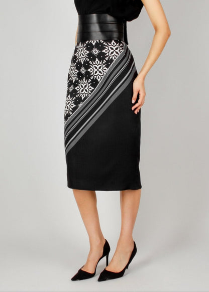 Elegant black midi skirt from the HORRA collection by MNour Design, featuring a bold asymmetrical keffiyeh-inspired pattern. Paired with a sleek black top and a structured leather waist belt for a modern, powerful look. Explore the full collection at www.mnourdesign.com.