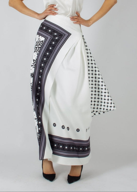 Elegant white maxi skirt from the HORRA collection by MNour Design, featuring intricate traditional-inspired patterns and a draped keffiyeh detail for a bold cultural statement. Paired with a sleek satin top and classic heels for a refined, sophisticated look. Discover more at www.mnourdesign.com