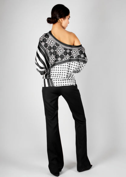 Bold off-shoulder blouse from the HORRA collection by MNour Design, featuring a striking keffiyeh-inspired pattern with intricate geometric details. Paired with sleek black trousers for a modern, sophisticated look. Explore more at www.mnourdesign.com