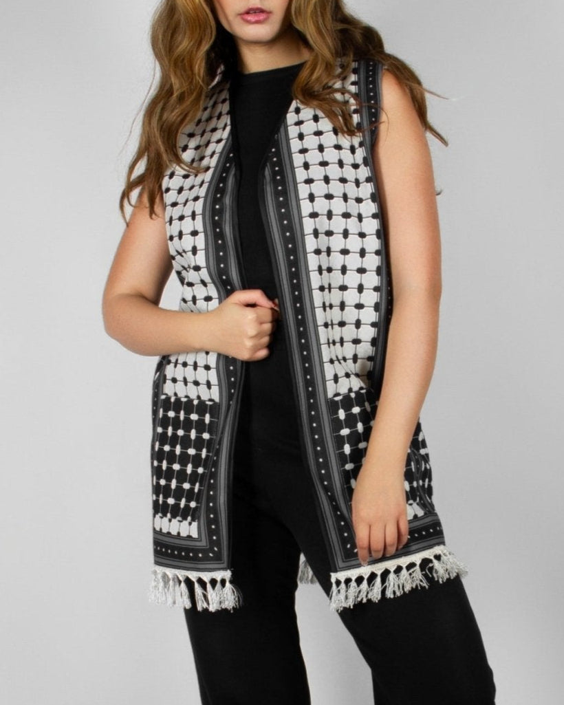 Modern black and white vest from the HORRA collection by MNour Design, featuring intricate geometric and traditional patterns with delicate fringe detailing. Styled over a sleek black ensemble for a contemporary yet culturally inspired look. Discover more at www.mnourdesign.com