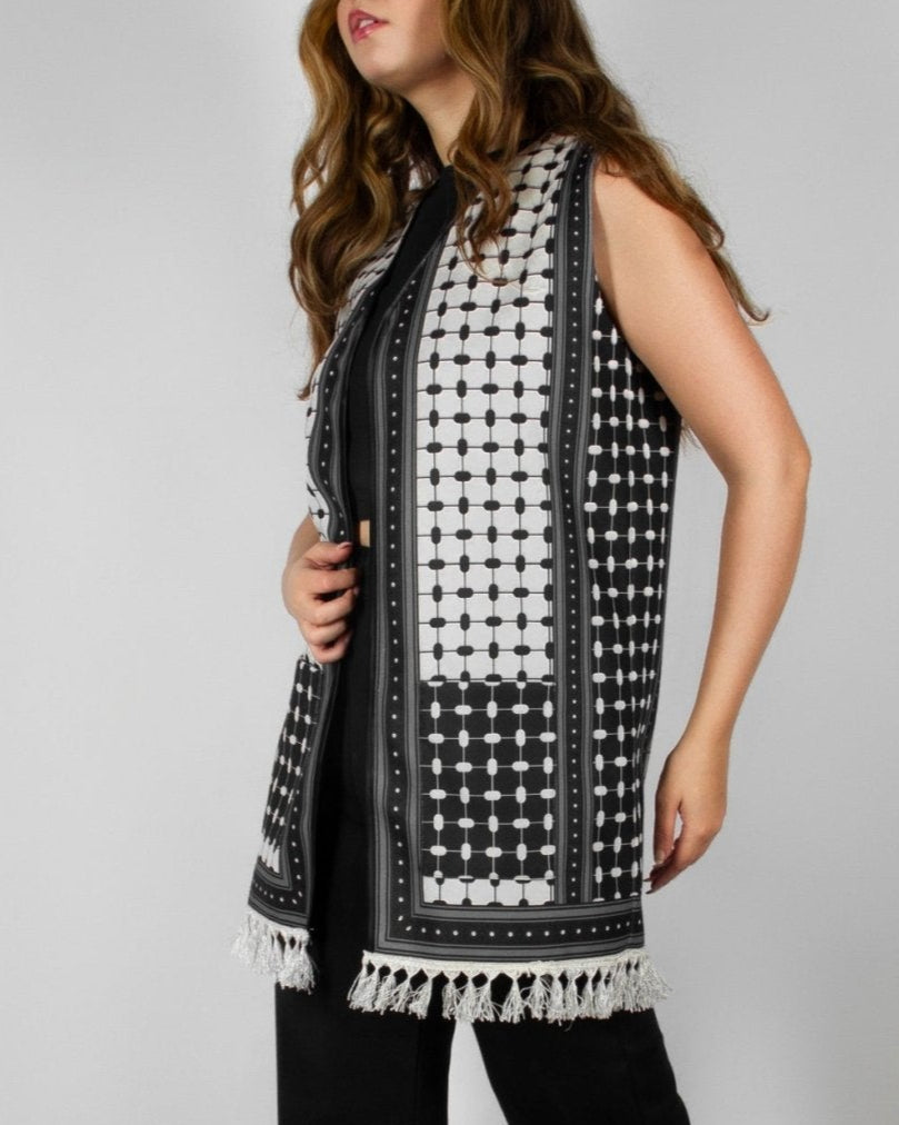 Modern black and white vest from the HORRA collection by MNour Design, featuring intricate geometric and traditional patterns with delicate fringe detailing. Styled over a sleek black ensemble for a contemporary yet culturally inspired look. Discover more at www.mnourdesign.com