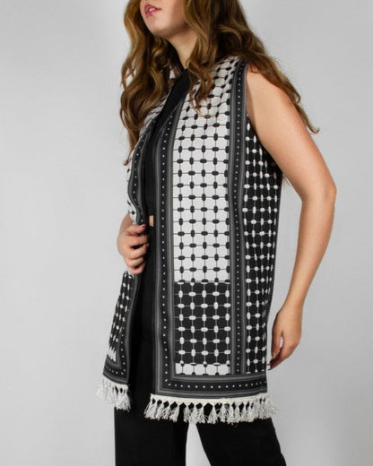 Modern black and white vest from the HORRA collection by MNour Design, featuring intricate geometric and traditional patterns with delicate fringe detailing. Styled over a sleek black ensemble for a contemporary yet culturally inspired look. Discover more at www.mnourdesign.com