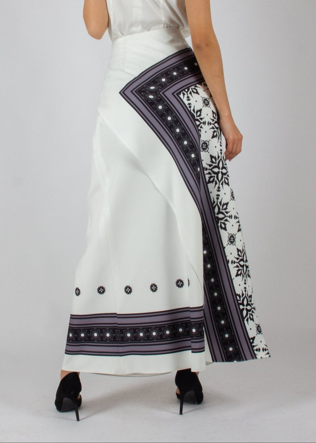 Elegant white maxi skirt from the HORRA collection by MNour Design, featuring intricate traditional-inspired patterns and a draped keffiyeh detail for a bold cultural statement. Paired with a sleek satin top and classic heels for a refined, sophisticated look. Discover more at www.mnourdesign.com