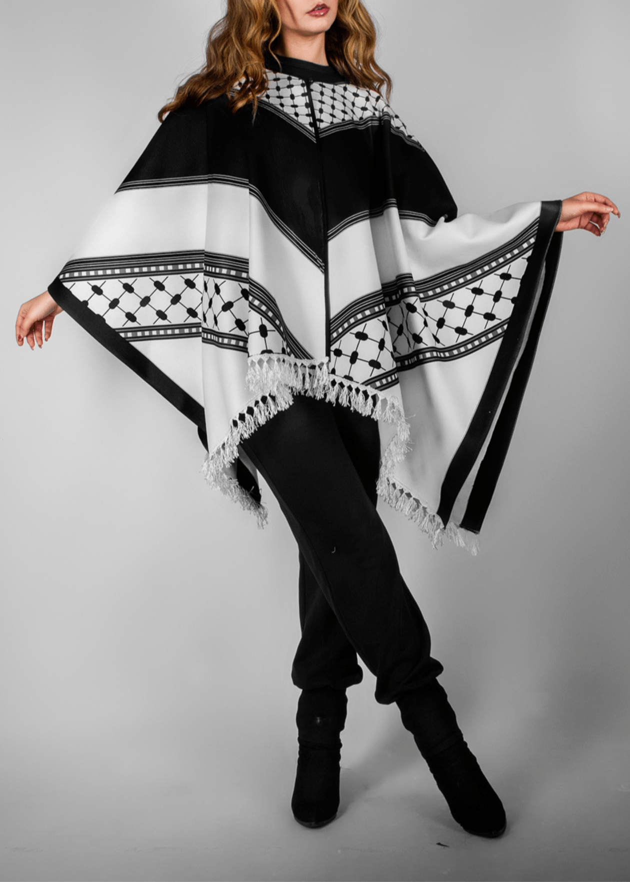 Elegant black and white poncho from the HORRA collection by MNour Design, inspired by traditional Palestinian keffiyeh patterns. Featuring intricate geometric details and delicate fringe edges, this timeless piece blends cultural heritage with modern sophistication. Discover more at www.mnourdesign.com
