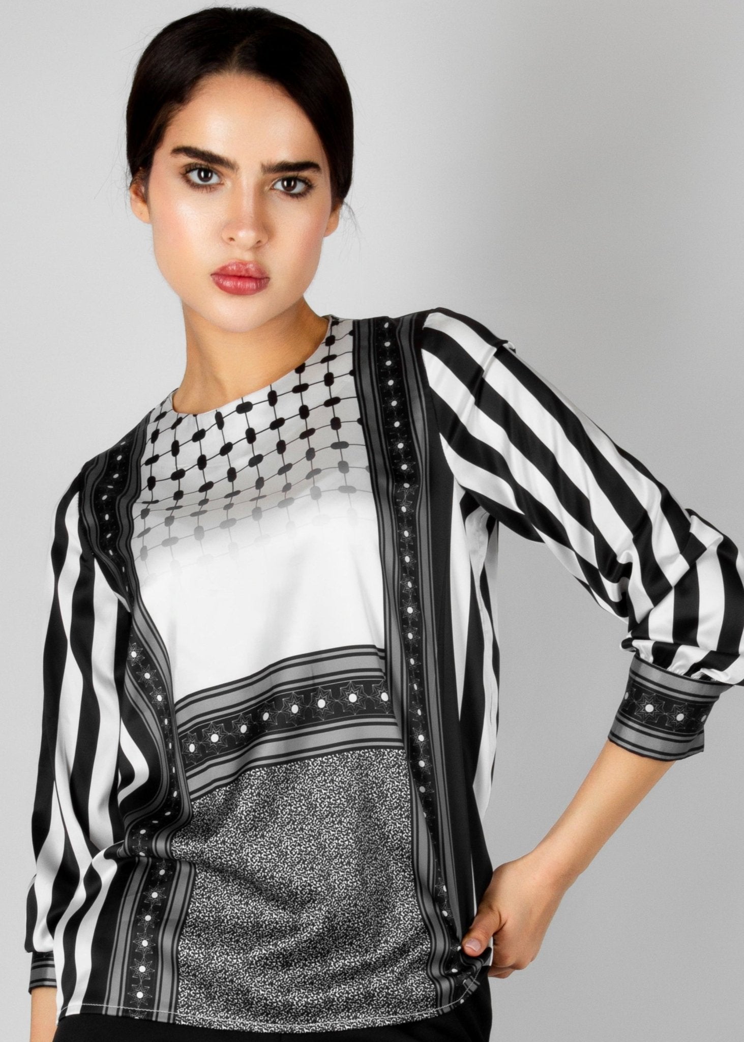 Modern black and white blouse from the HORRA collection by MNour Design, featuring keffiyeh-inspired patterns and bold stripes. A sophisticated fusion of heritage and contemporary fashion. Explore more at www.mnourdesign.com