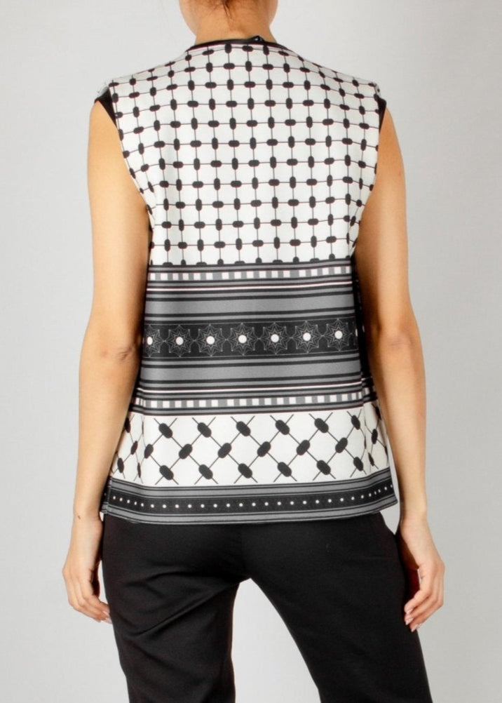 Modern sleeveless vest from the HORRA collection by MNour Design, featuring a striking black-and-white keffiyeh-inspired pattern. Styled with a sleek black satin blouse and tailored trousers for a bold and sophisticated look. Discover more at www.mnourdesign.com