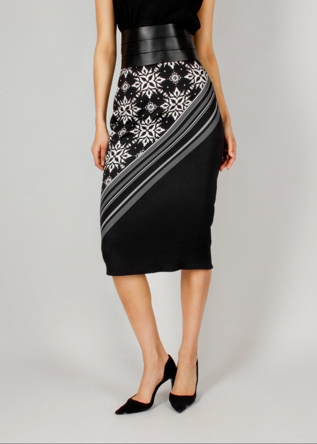 Elegant black midi skirt from the HORRA collection by MNour Design, featuring a bold asymmetrical keffiyeh-inspired pattern. Paired with a sleek black top and a structured leather waist belt for a modern, powerful look. Explore the full collection at www.mnourdesign.com.
