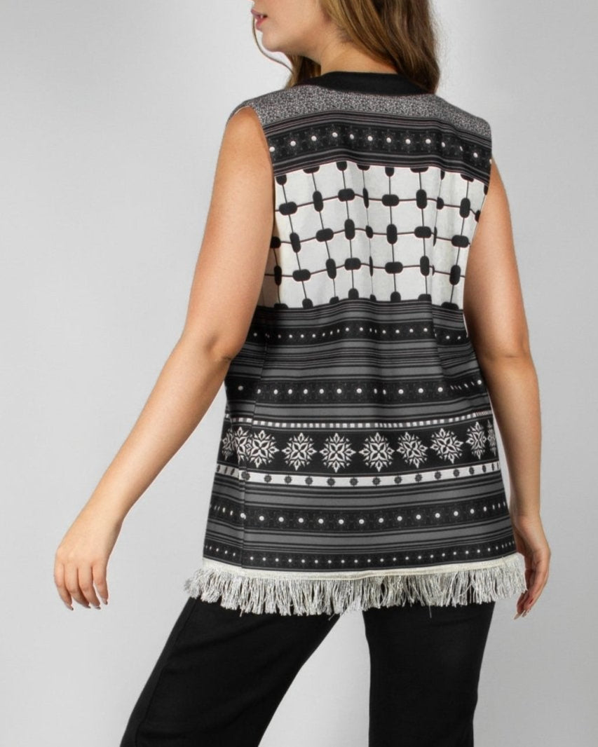 Modern black and white vest from the HORRA collection by MNour Design, featuring intricate geometric and traditional patterns with delicate fringe detailing. Styled over a sleek black ensemble for a contemporary yet culturally inspired look. Discover more at www.mnourdesign.com
