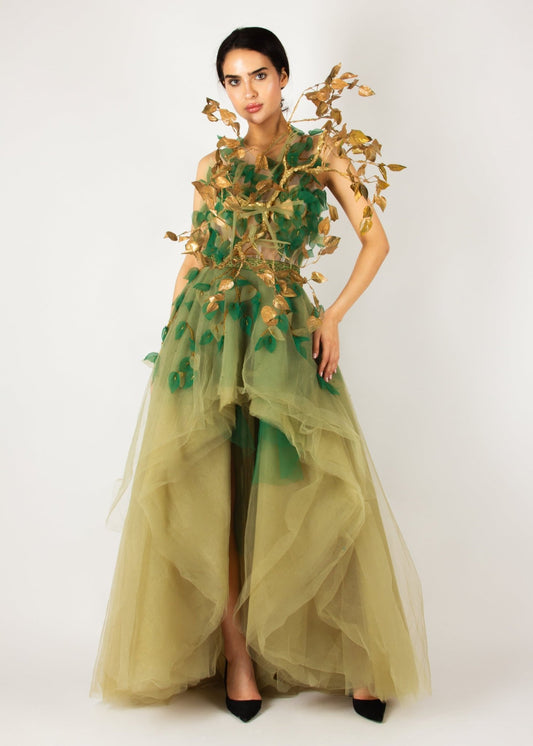 Enchanting nature-inspired gown by MNour Design, featuring a flowing olive-green tulle skirt with a high-low cut and an intricately designed bodice adorned with gold and green leaf appliqués. A breathtaking fusion of fashion and artistry. Discover this exclusive design at www.mnourdesign.com