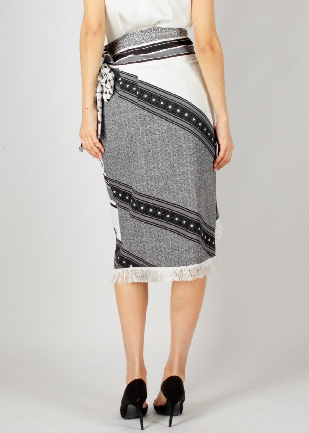 Chic wrap-style midi skirt from the HORRA collection by MNour Design, featuring a striking black-and-white traditional pattern with fringe detailing and a statement side tie. Paired with a sleek satin top and classic heels for an effortlessly elegant look. Explore more at www.mnourdesign.com