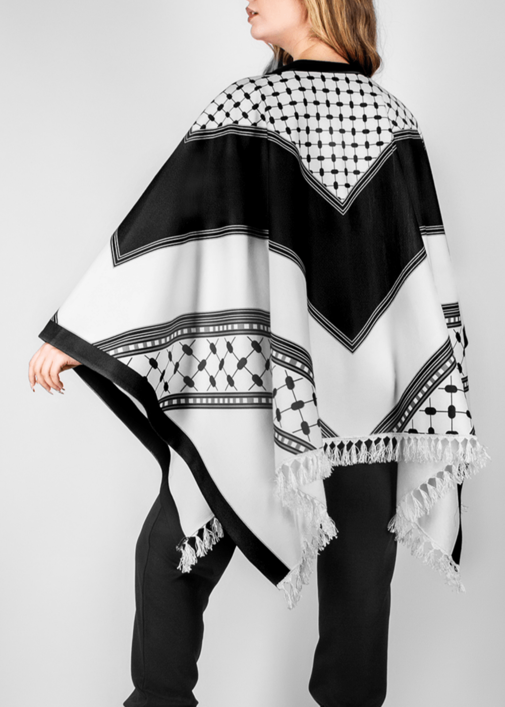 Elegant black and white poncho from the HORRA collection by MNour Design, inspired by traditional Palestinian keffiyeh patterns. Featuring intricate geometric details and delicate fringe edges, this timeless piece blends cultural heritage with modern sophistication. Discover more at www.mnourdesign.com