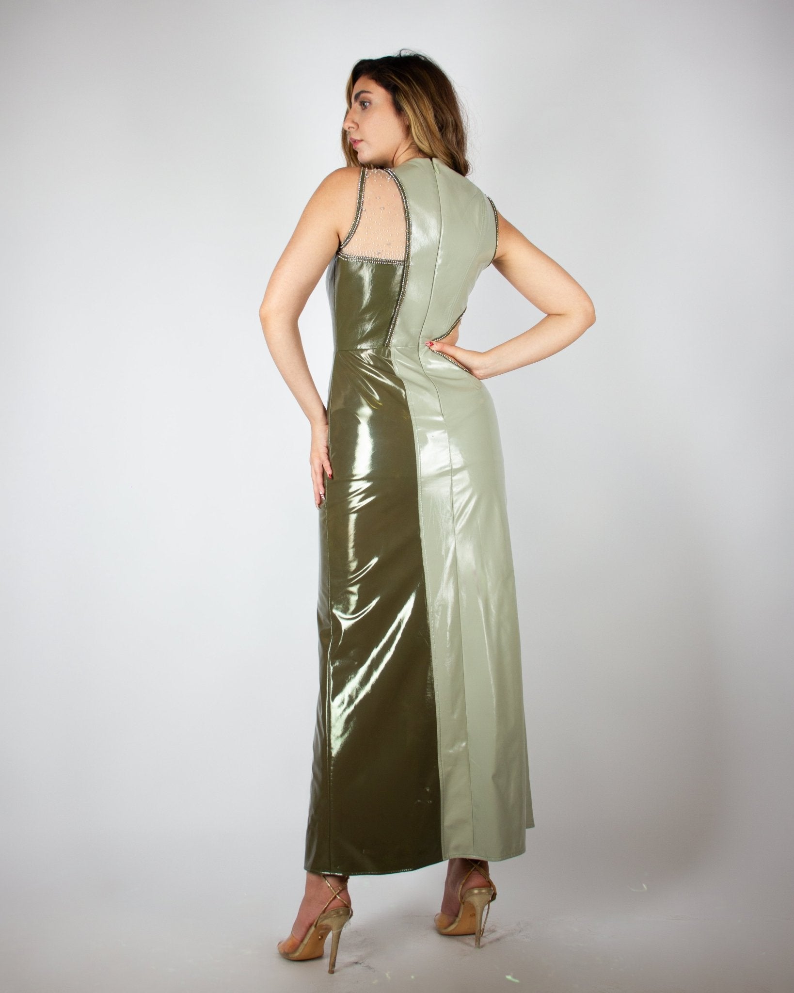 Sleek and modern olive-green evening gown by MNour Design, featuring a glossy latex-like finish, asymmetrical cut-out details, and a high slit adorned with shimmering embellishments. A bold fusion of elegance and contemporary fashion. Explore this statement piece at www.mnourdesign.com
