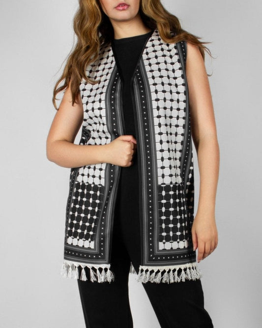 Modern black and white vest from the HORRA collection by MNour Design, featuring intricate geometric and traditional patterns with delicate fringe detailing. Styled over a sleek black ensemble for a contemporary yet culturally inspired look. Discover more at www.mnourdesign.com