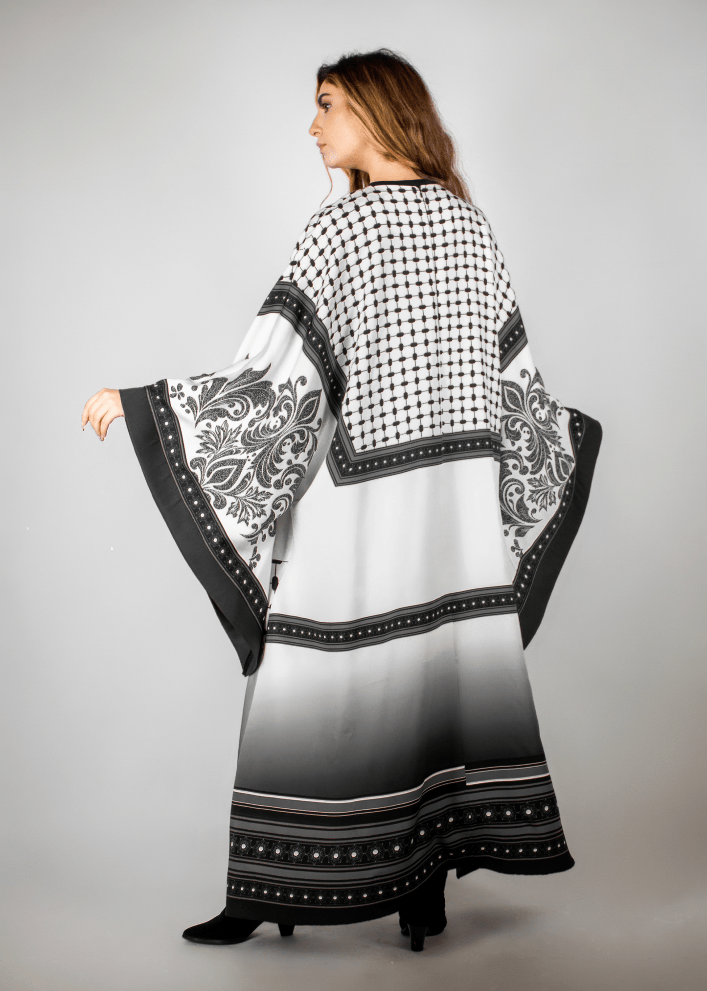 Elegant black and white abaya from the HORRA collection by MNour Design, featuring intricate architectural patterns and cultural motifs. A sophisticated blend of heritage and modern fashion. Discover more at www.mnourdesign.com