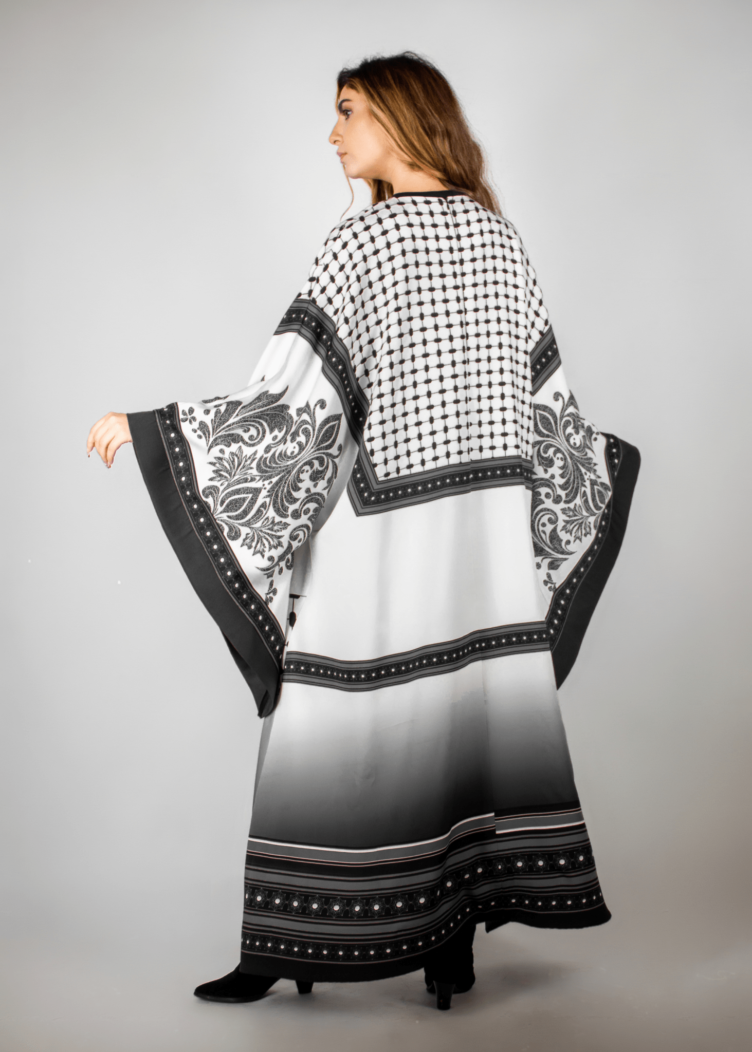 Elegant black and white abaya from the HORRA collection by MNour Design, featuring intricate architectural patterns and cultural motifs. A sophisticated blend of heritage and modern fashion. Discover more at www.mnourdesign.com