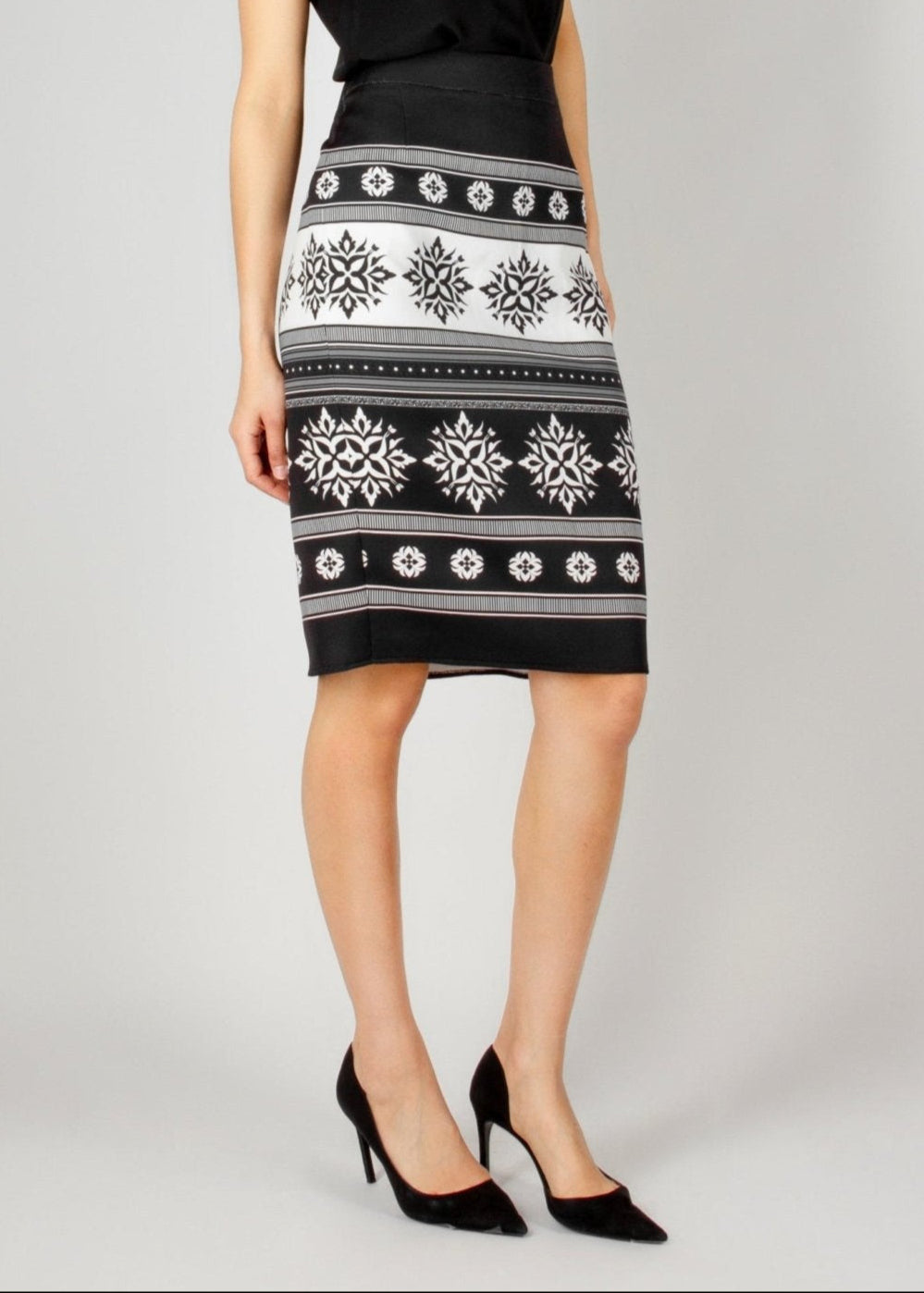 Chic black and white pencil skirt from the HORRA collection by MNour Design, featuring traditional keffiyeh-inspired embroidery. Paired with a sleek black V-neck top and classic black heels for an elegant yet modern look. Discover more at www.mnourdesign.com.