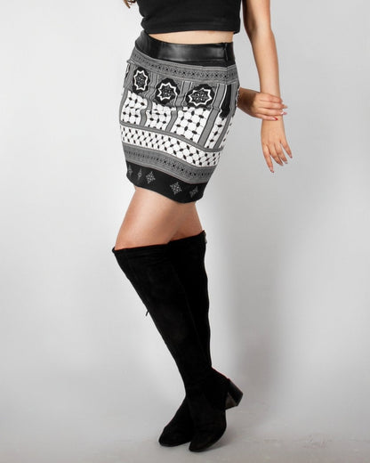 Chic black and white patterned skirt from the HORRA collection by MNour Design, featuring intricate geometric and traditional motifs with a modern leather waistband. Styled with a sleek black crop top and knee-high boots for an effortlessly elegant look. Explore more at www.mnourdesign.com
